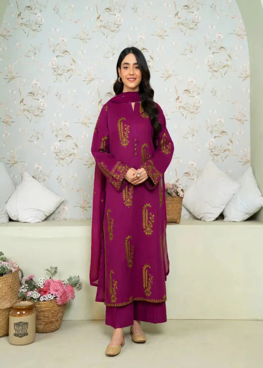 Woman wearing a purple embroidered outfit standing in a room with floral wallpaper and decorative items.