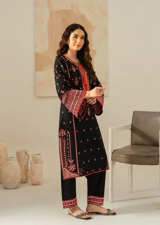 Woman wearing a black and red embroidered outfit in a minimalistic room.